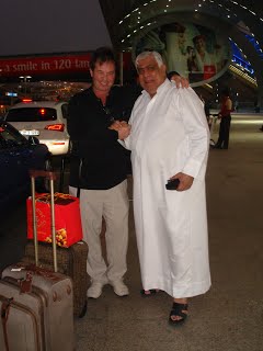 Photo of Thomas Schoenberger with an older man in a white thobe at an airport, with luggage